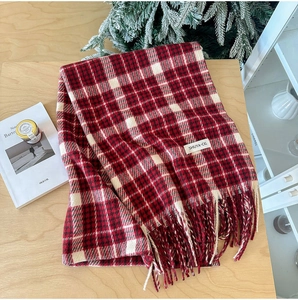 Detailed close-up of thick plaid cashmere-like scarf with fringe and brand label