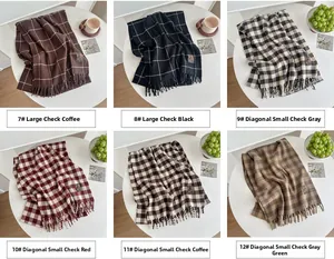 Detail of soft cashmere-like fringe scarves with plaid and twill patterns in neutral tones