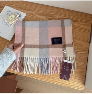 Detail of plaid wool scarf with tassel edge, logo label and elegant brand tags