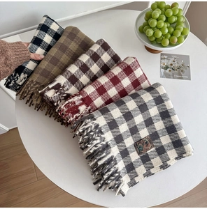 Close-up of assorted plaid scarves with fringe details and vintage embroidery labels