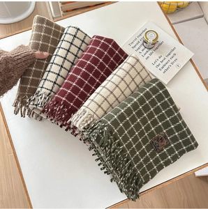 Detail of five soft plaid scarves with fringe in autumn colors on a wooden table