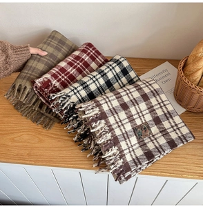 Close-up of assorted plaid scarves with fringe and retro labels on wooden table