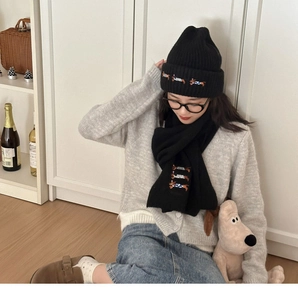 Detailed embroidery of a dachshund dog on a black knitted wool hat and matching winter scarf