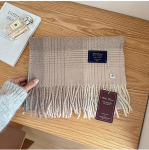 Close-up of classic plaid wool scarf with fringe edges and 10% wool label detail