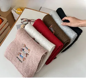 Close-up of wool scarves in multiple colors featuring embroidered dachshund details