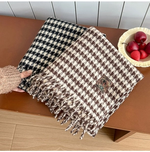 Detail of plaid houndstooth scarves featuring fringed edges and vintage brand woven labels