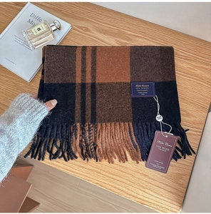 Detailed close-up of British plaid wool scarf with fringes on a wooden background