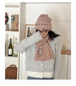 Detail of pink knitted hat and scarf set featuring embroidered dachshund dog patterns