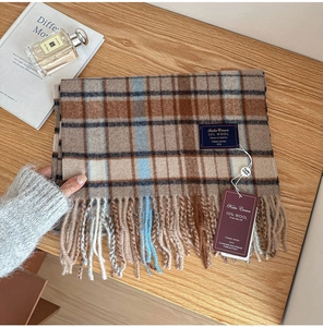 Classic British wool blend plaid scarf with elegant fringe detail on a rustic wood surface