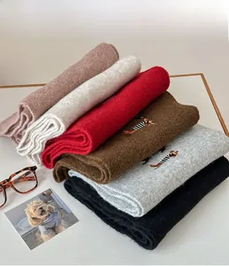 Detailed view of knitted wool scarves in six colors featuring cute dog embroidery