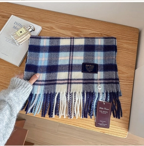 Detailed shot of a classic blue plaid wool scarf with fringes on a rustic wooden desk