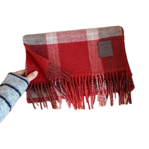 Red plaid wool scarf with fringes and brown leather label for autumn and winter