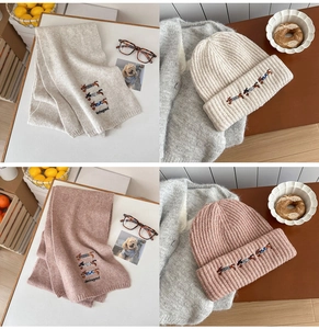 Detail of embroidered dachshund and knit texture on the winter scarf and hat set
