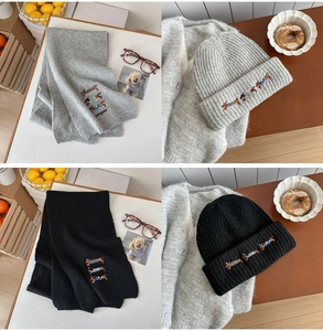 Detail of embroidered dachshund dog pattern on knitted wool scarf and matching hat set