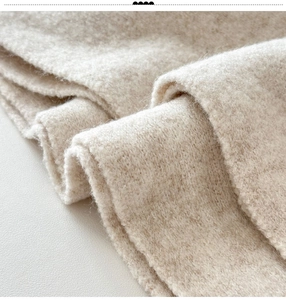 Detailed macro shot of soft oatmeal beige wool knit fabric with warm plush texture
