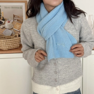 Detail of sky blue rib-knit scarf with delicate bow embroidery and soft wool texture