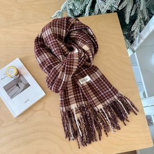 Classic plaid imitation cashmere scarf with tassels and label on a wooden desk