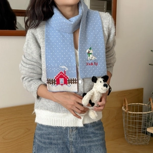 Detail of light blue knit scarf with festive house embroidery and white polka dots