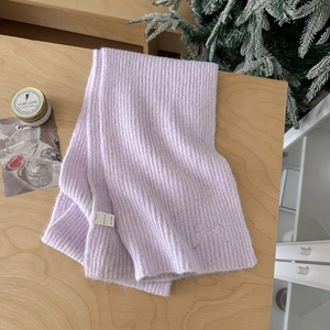 Detail of lavender wool blend knit scarf with embroidered bow on a wooden surface