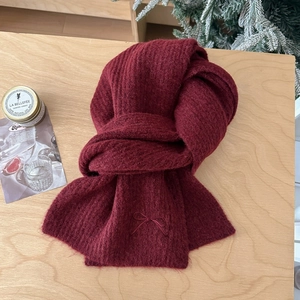 Detail view of burgundy knit scarf featuring elegant bow embroidery and soft wool texture