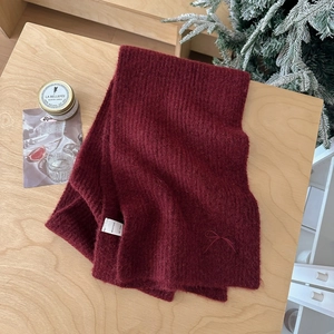 Detailed macro view of burgundy knit scarf texture with a silk ribbon bow and label