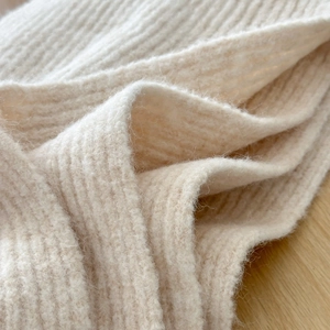 Detailed macro view of cream-colored ribbed knit wool fabric texture and soft fibers
