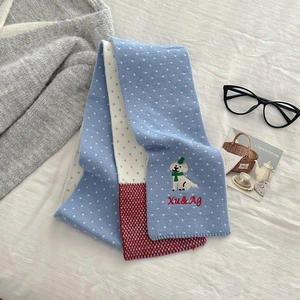Close-up of knit scarf featuring cute puppy embroidery and red white plaid patterns