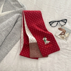 Close-up of winter knit scarf with white dog embroidery and red polka dot pattern
