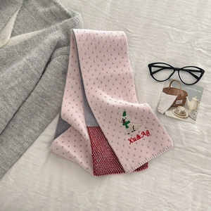 Detail of pink and gray knit scarf featuring cute puppy embroidery and dot pattern