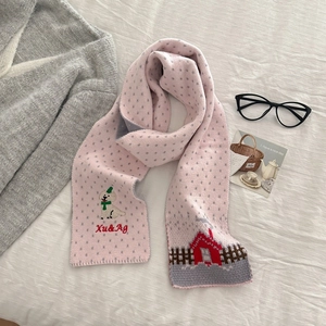 Pink knit scarf detail with embroidered puppy motif and dot pattern on a soft fabric