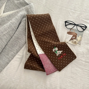 Detailed view of knitted polka dot scarf with puppy embroidery and Xu & Ag branding