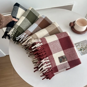 Winter plaid tassel scarves in multiple colors stacked on table for warm winter style