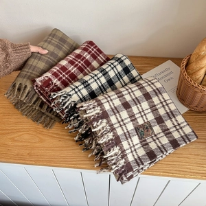 Set of four plaid tassel scarves in classic patterns on a cozy wooden tabletop