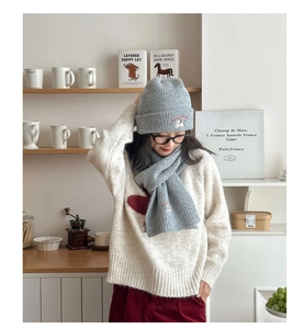 Detail of grey knitted hat and scarf set with white puppy embroidery for winter