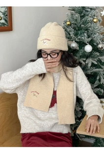 Close-up of cream knit hat and scarf set with lucky puppy embroidery for winter