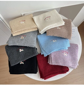 Close-up of knit scarves set with white puppy embroidery and ribbed edge detailing