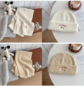 Detailed close-up of knitted winter scarf and beanie set with dog embroidery