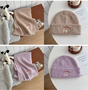 Detailed close-up of ribbed knit scarf and hat set with cute dog embroidery and lettering