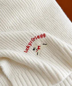 Detailed view of white knitted fabric with cute puppy and Lucky PiPi Egg embroidery