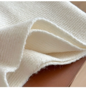 Close-up of thick cream ribbed knit fabric texture showing soft material detail
