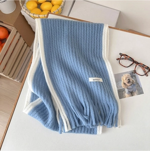 Détail d'une écharpe en mohair bleu et blanc avec texture côtelée, franges et étiquette tissée