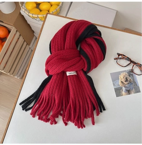 Gros plan sur une écharpe en mohair rouge et noir avec texture tricotée et des franges