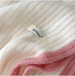 Gros plan sur la texture mohair moelleuse avec détails tricotés crème et roses