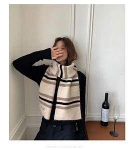 Detail of wool blend striped scarf showing knit texture and premium brand label on white fabric