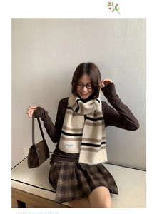 Detail of beige and brown striped wool blend scarf with woven brand label on a model