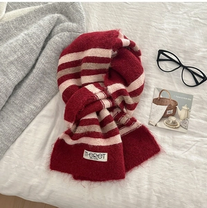 Close-up of red and white striped knit wool scarf with premium woven brand label