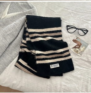 Detail shot of striped wool blend scarf texture with minimalist brand label on fabric