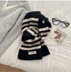 Detail of soft striped knit scarf with brand label on a cozy lifestyle background