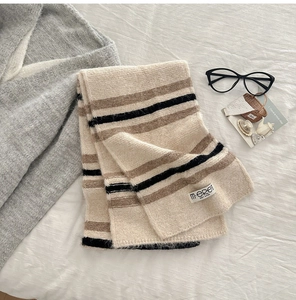 Close-up of wool blend striped scarf with beige, mocha, and black knit textures