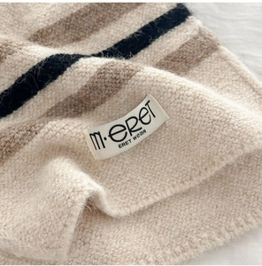 Close-up of wool blend striped knit fabric texture with m.eret brand woven label